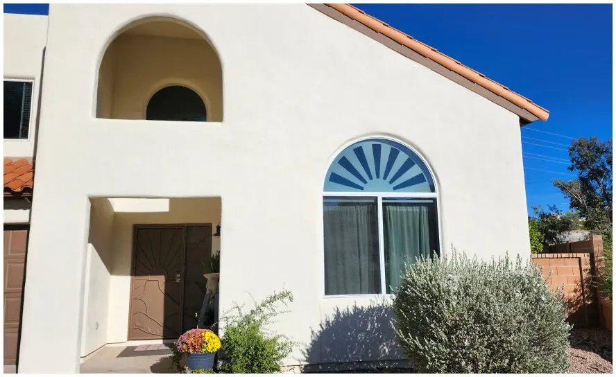 Stucco house with arched window and door.